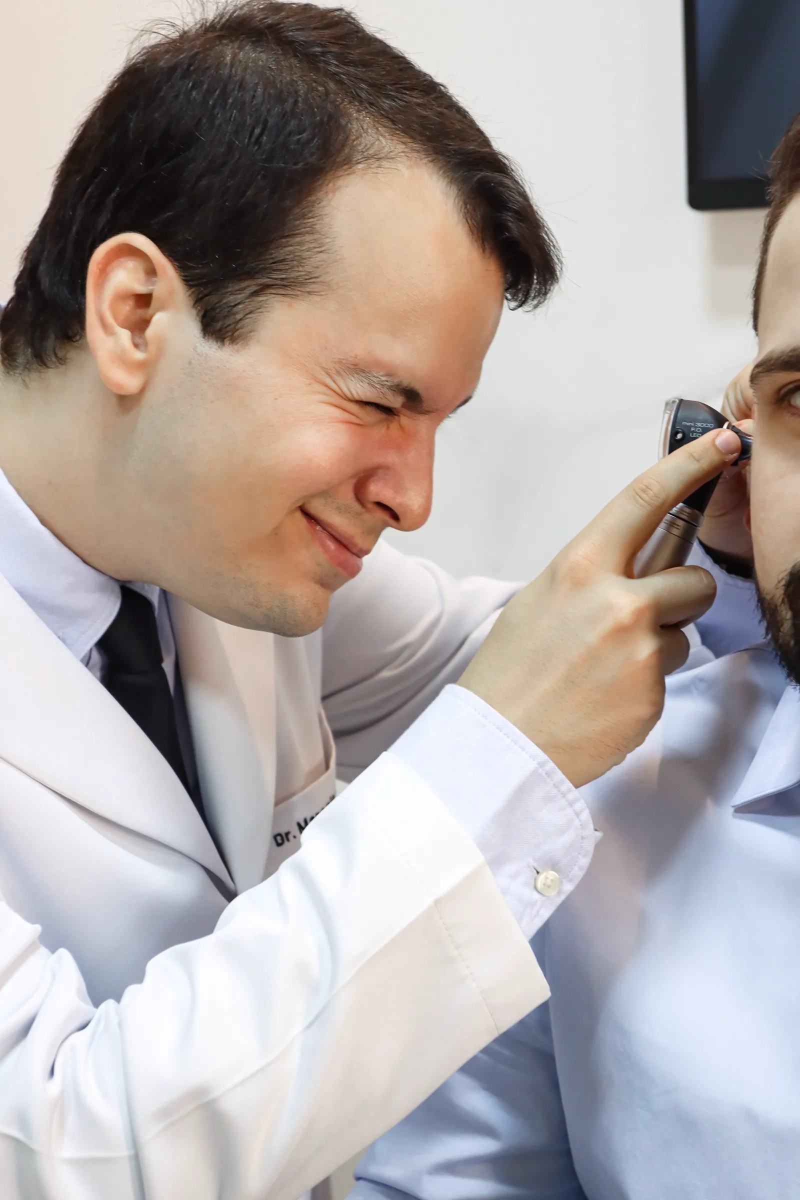 Dr. Marcelo examinando o nariz de um paciente no consultório