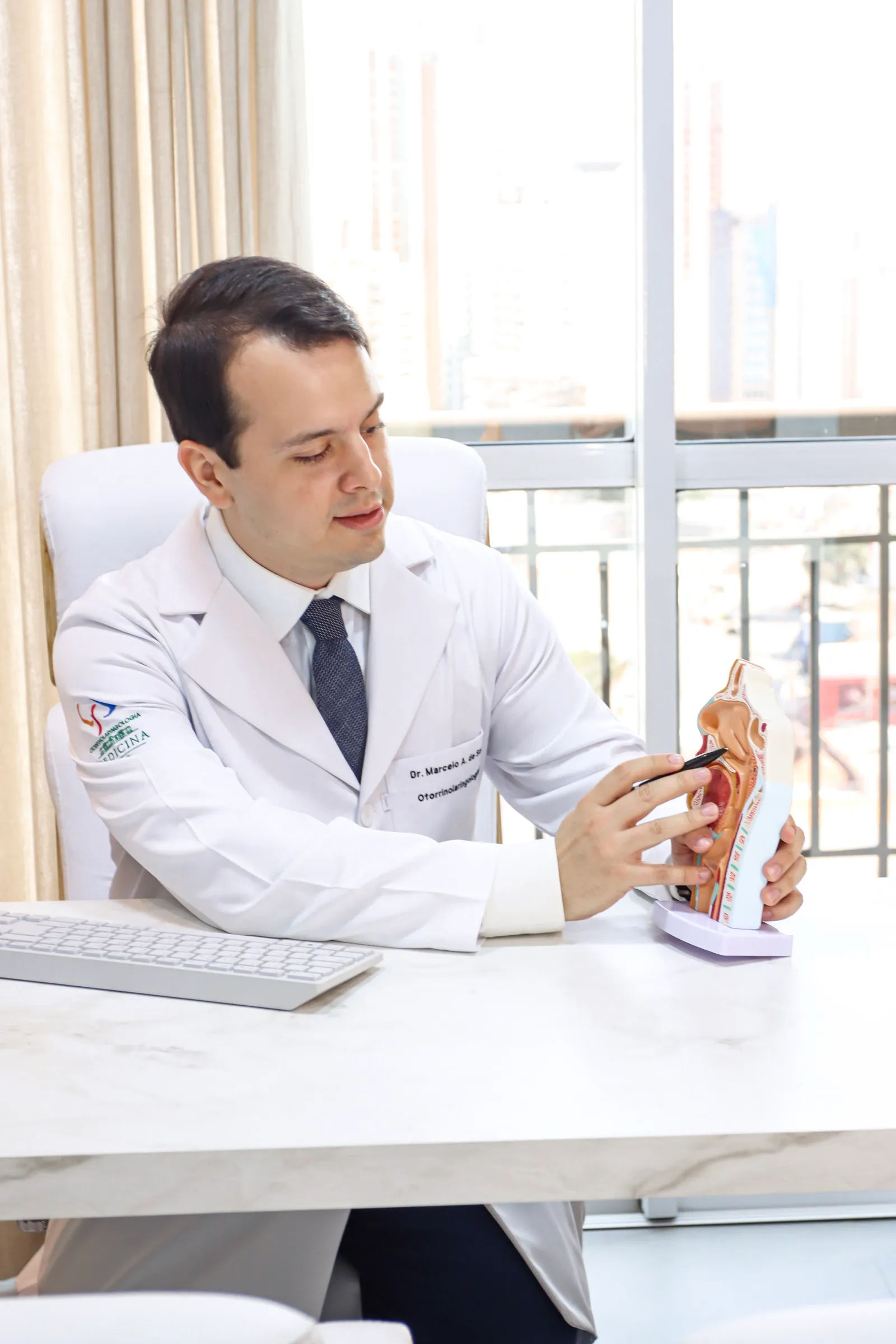 Dr. Marcelo com um modelo anatômico da cabeça no consultório
