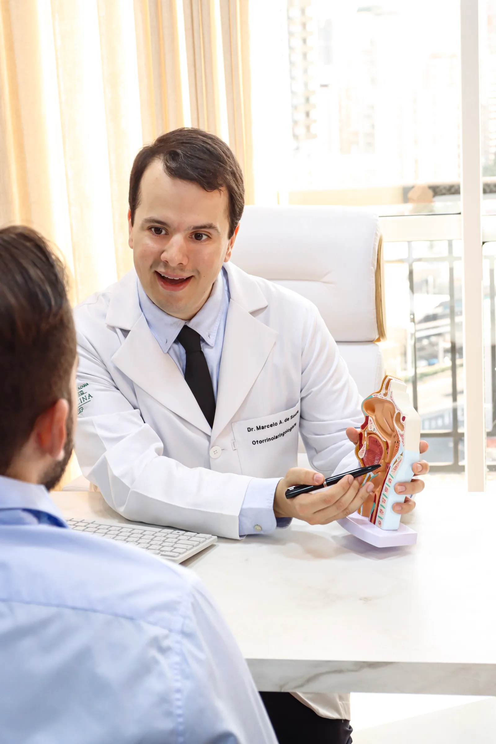 Dr. Marcelo conversando com paciente e mostrando um modelo anatômico durante a consulta